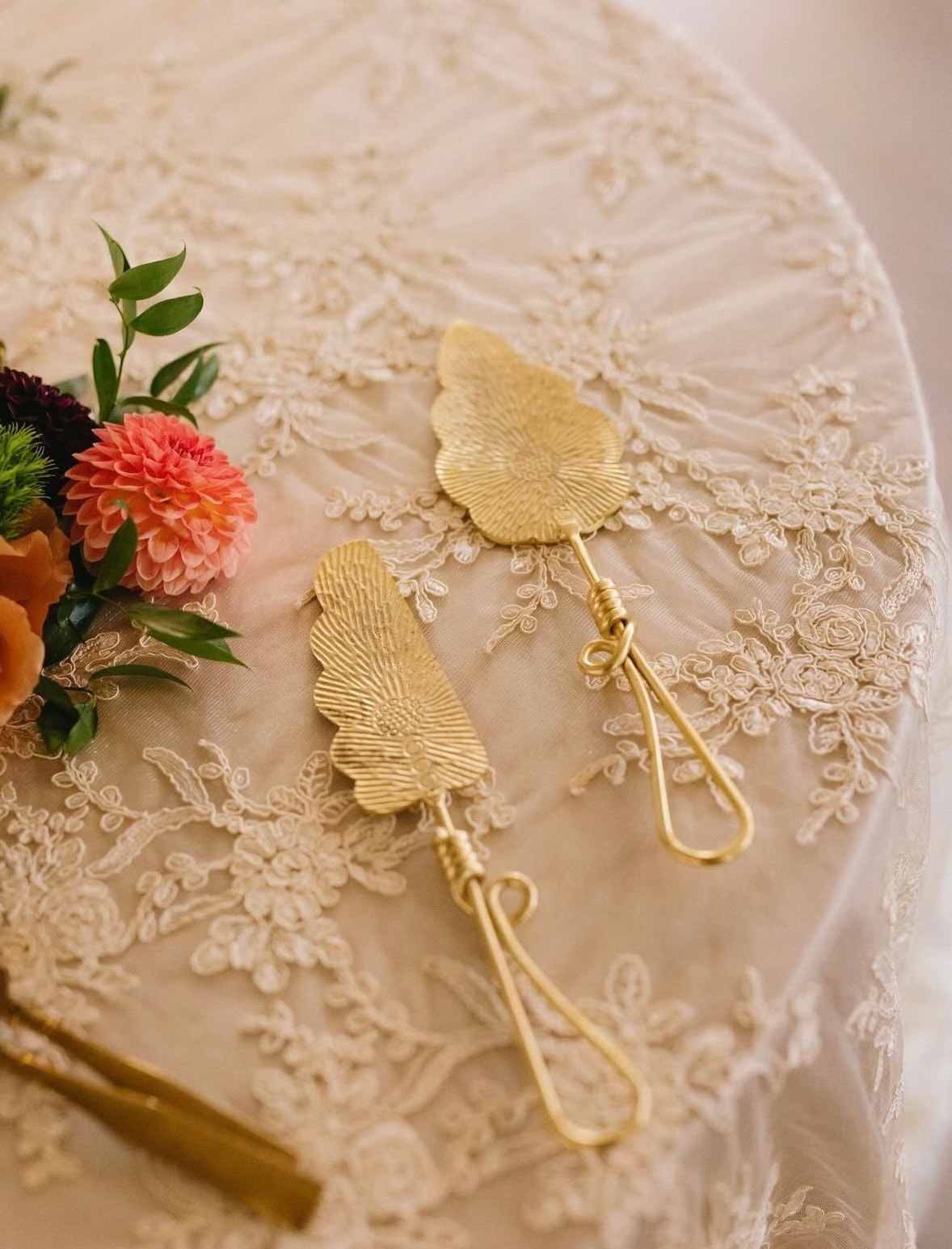 Gold leaf earrings on elegant cream lace linen with coral flowers